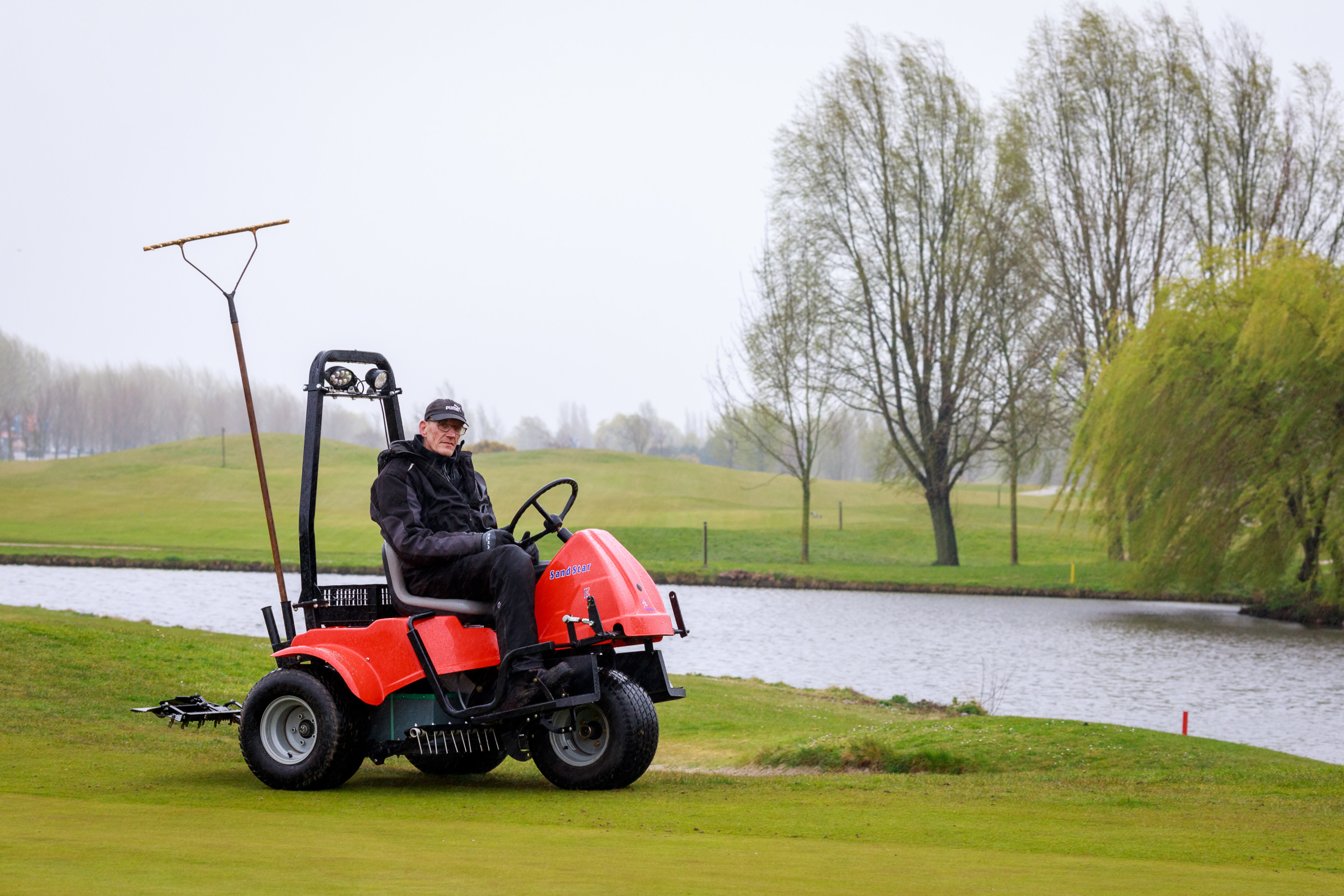 Medewerker Golfbaan rijdt met karretje voor baanonderhoud